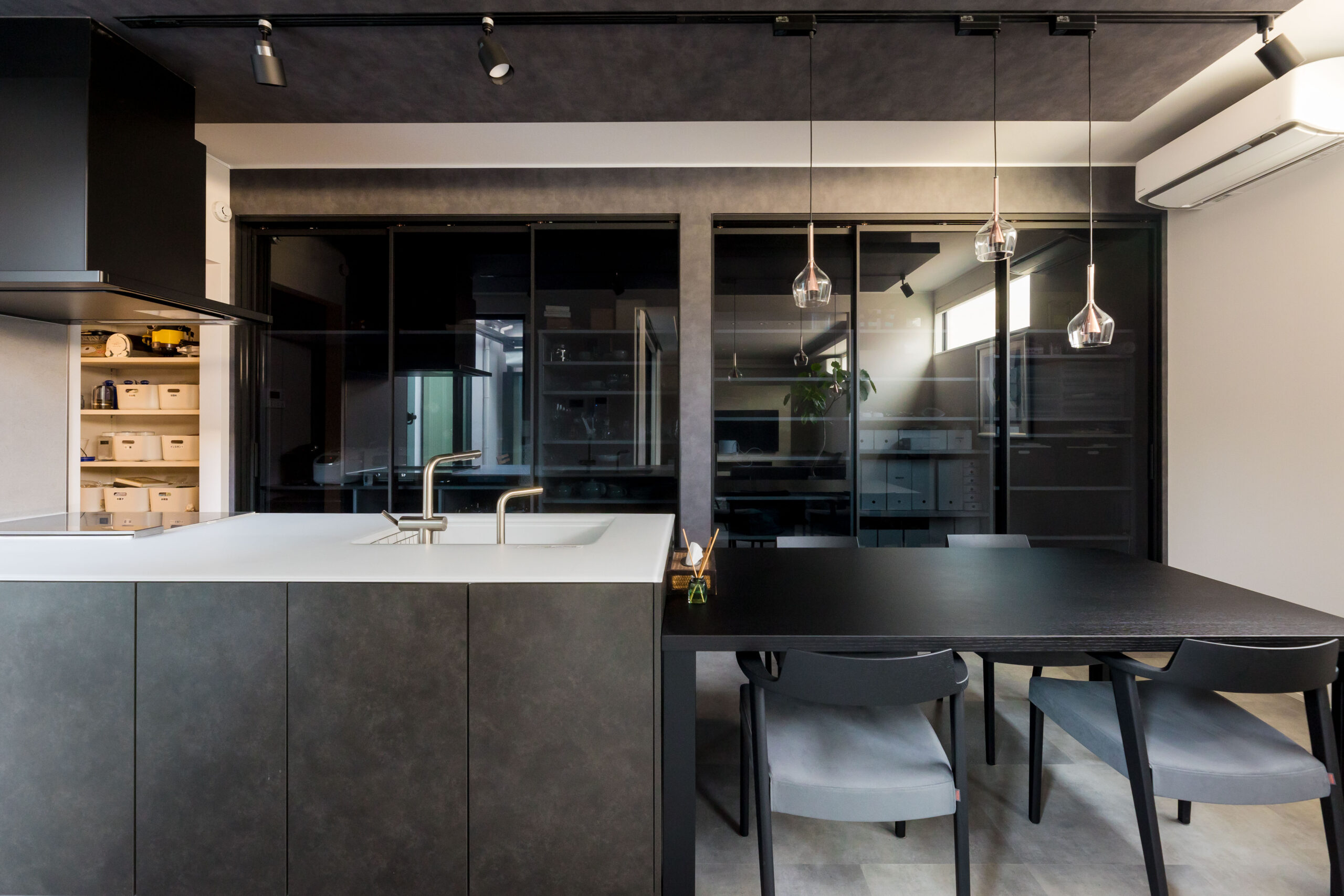 キッチンダイニングの背面に黒いガラス引き戸で隠した大容量収納